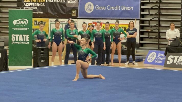 Senior gymnast Katie Barker competes in the individual floor exercise while her teammates cheer her on.